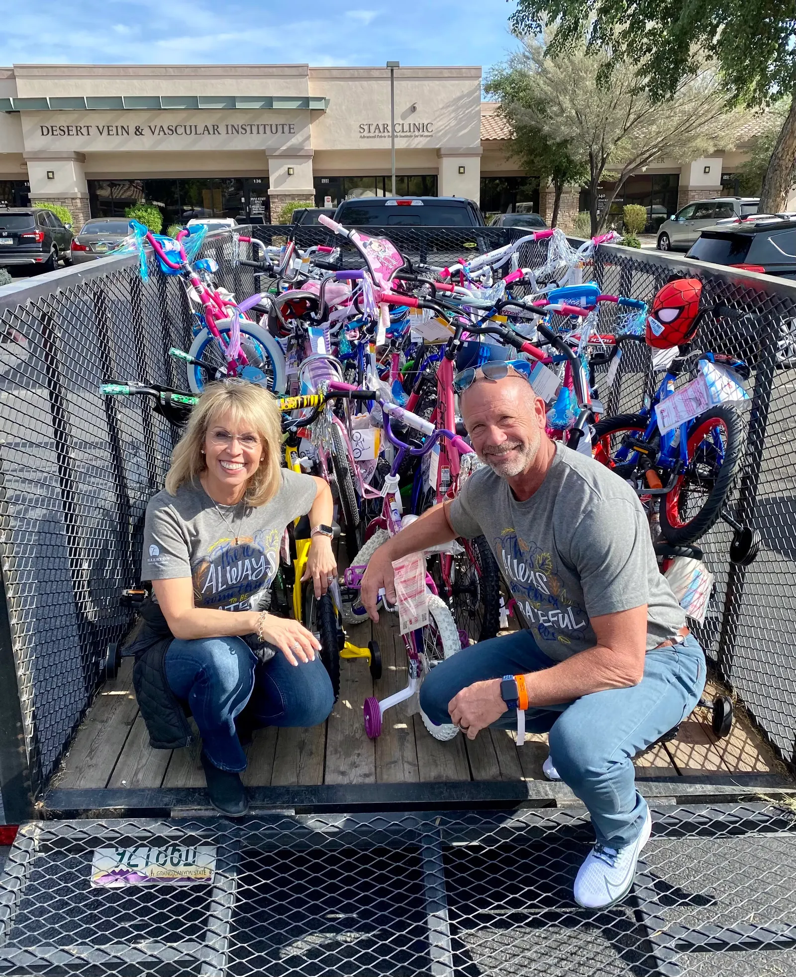Steve and Stephanie Fullerton kneeling in a trailer filled with donated bicycles