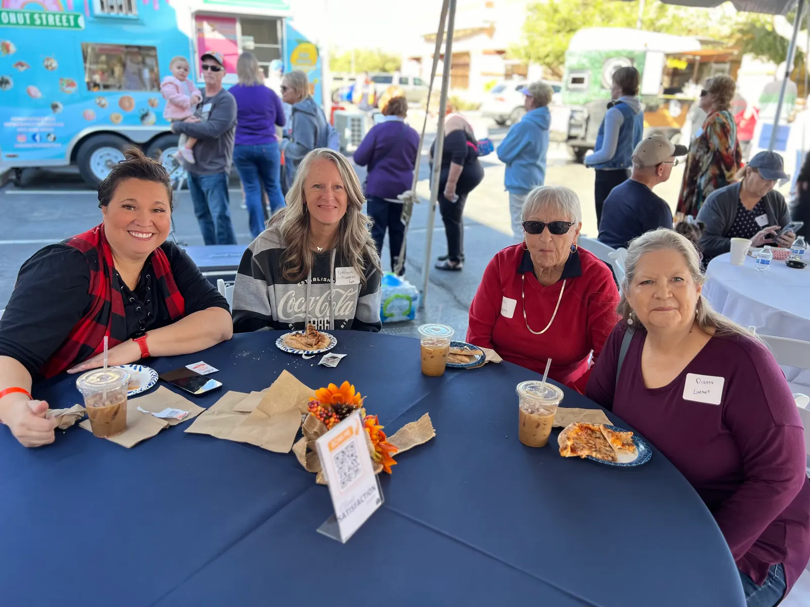 Guests seated at a table with a food truck behind them