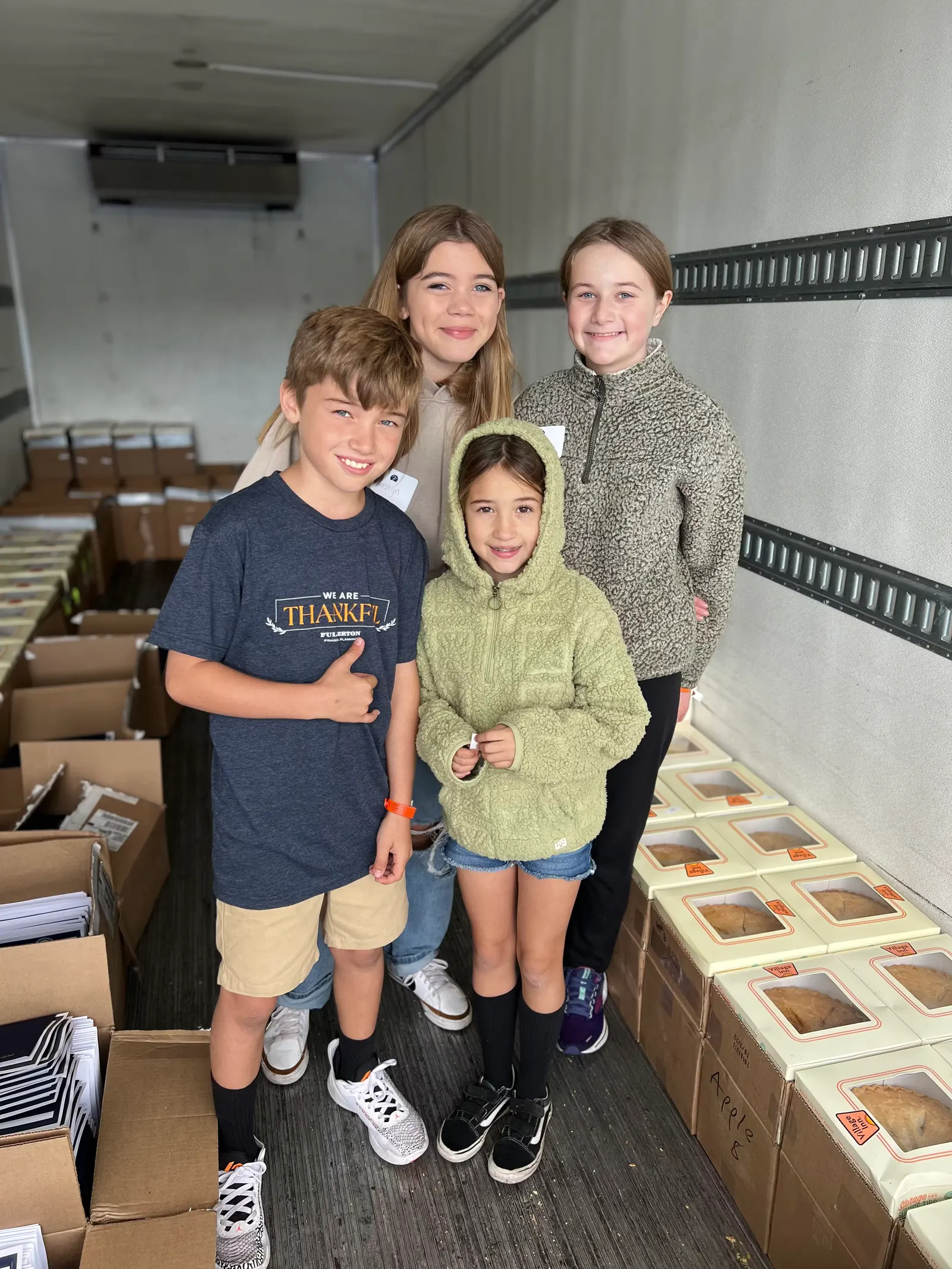Children standing in a truck among boxes of pie