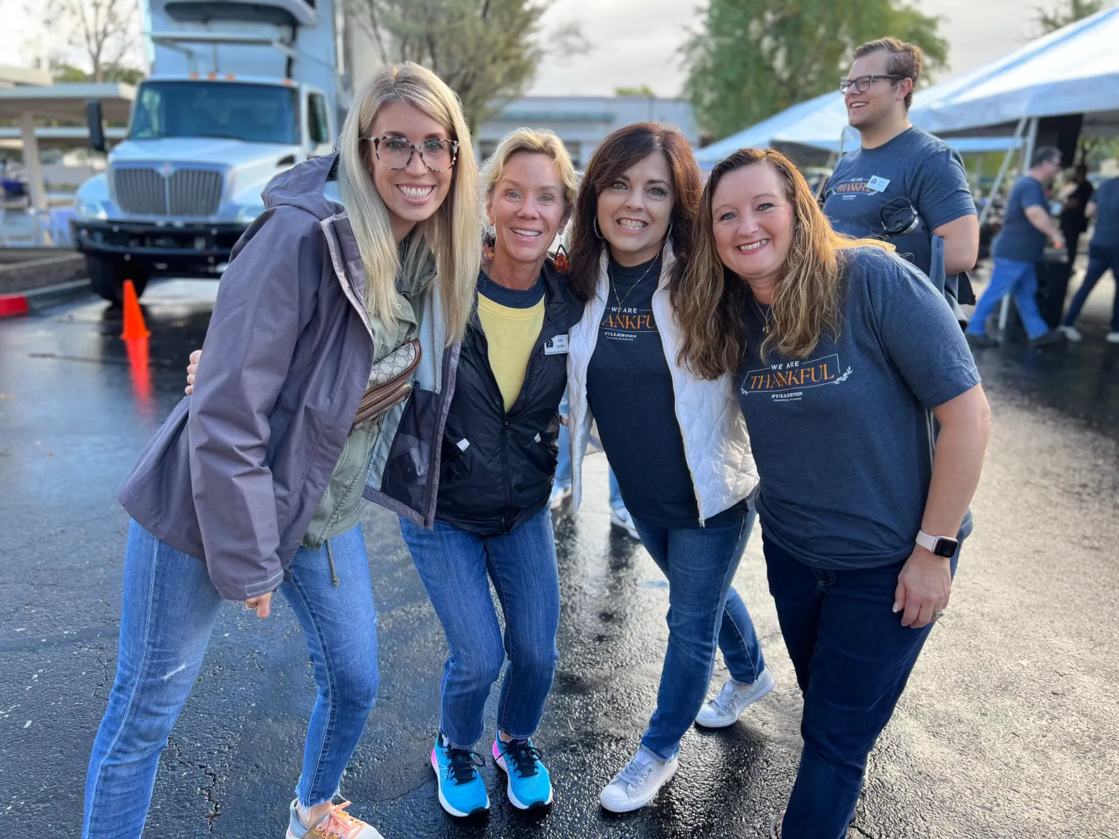 Four teammates in We Are Thankful shirts in front of the donation truck